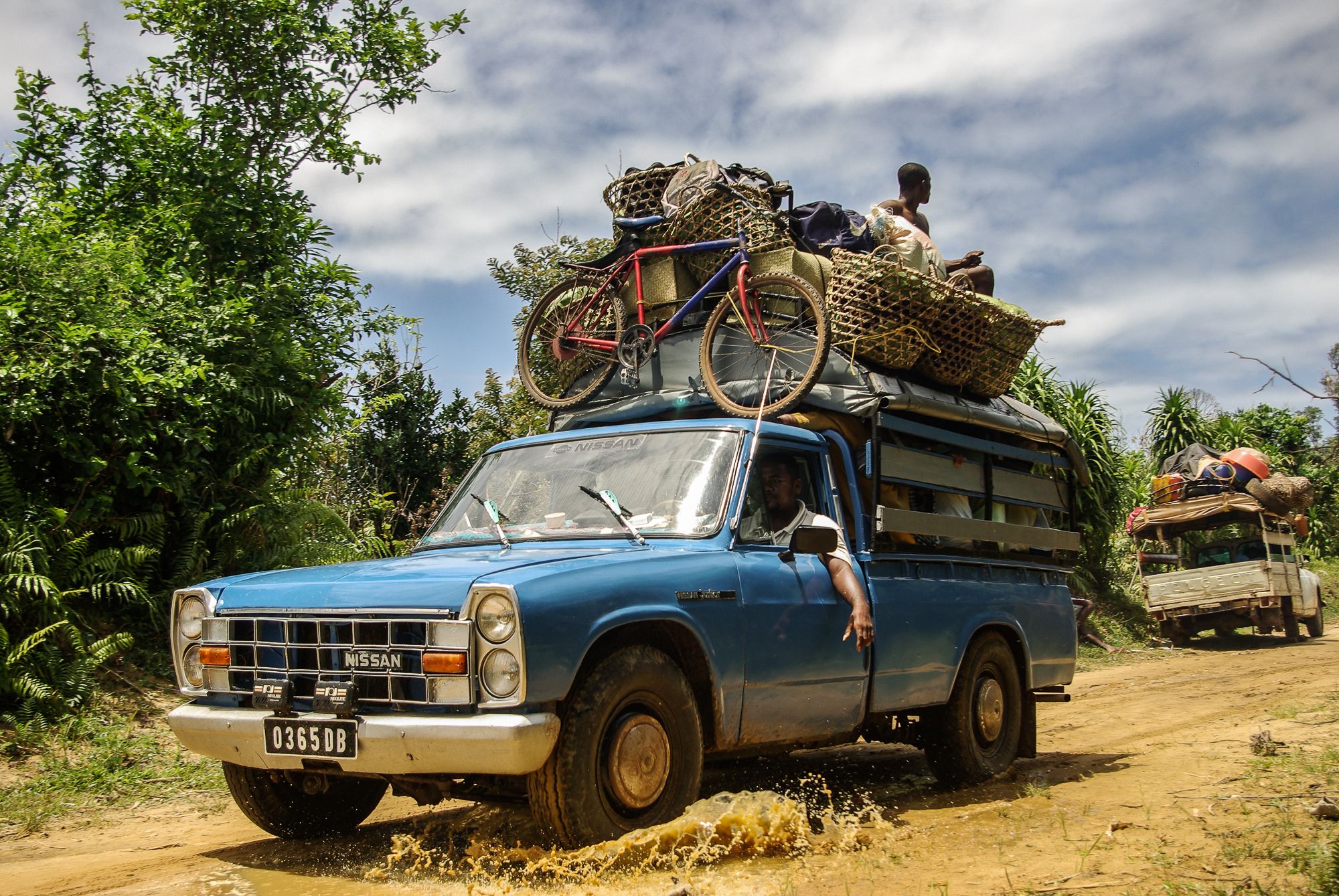 taxi-brousse nissan bleu transportant un vélo sur les pistes de Madagascar